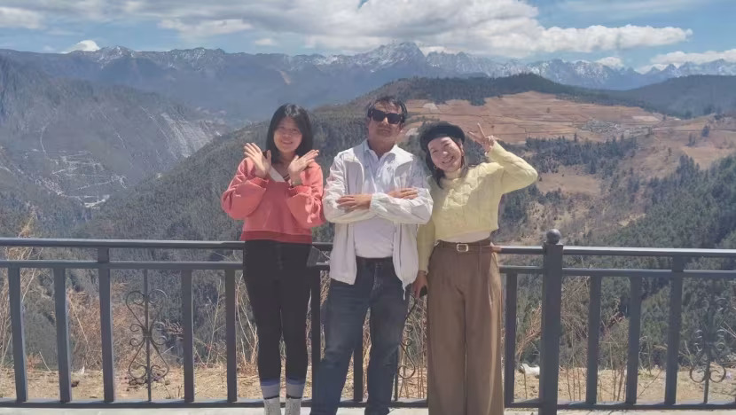 Chartered driver He Quan poses with Malaysian tourists he drove for in front of Haba Snow Mountain in Shangri-La city, China.